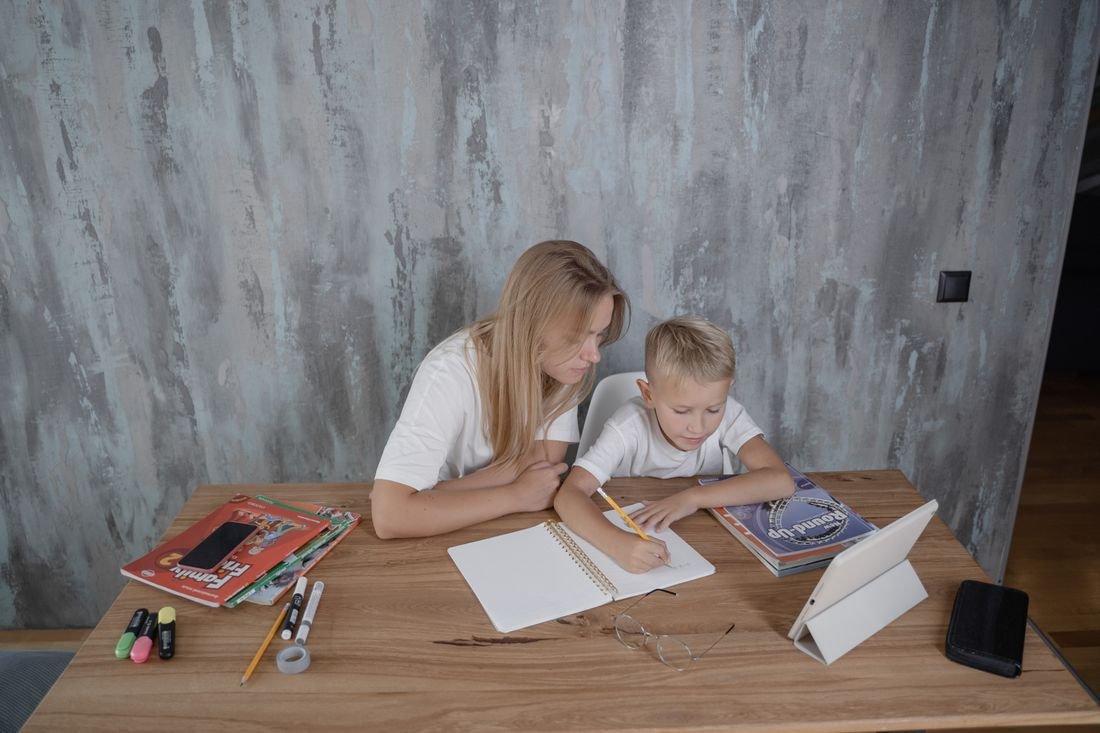 Un adulte accompagne un enfant dans son travail scolaire